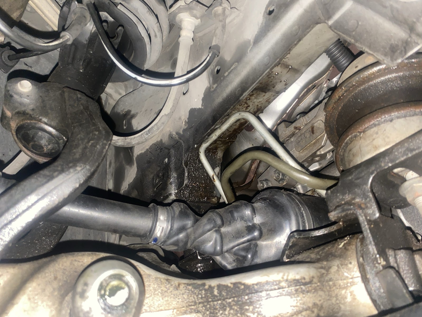 Looking up at a car's underside while tracing where a fluid leak starts