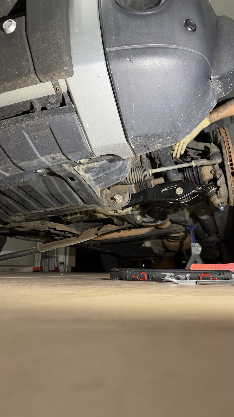 New suspension parts installed under a lifted truck at night, work light on the garage floor